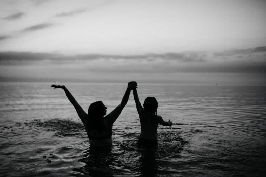 silhouette of mother and daughter jumping in water at night
