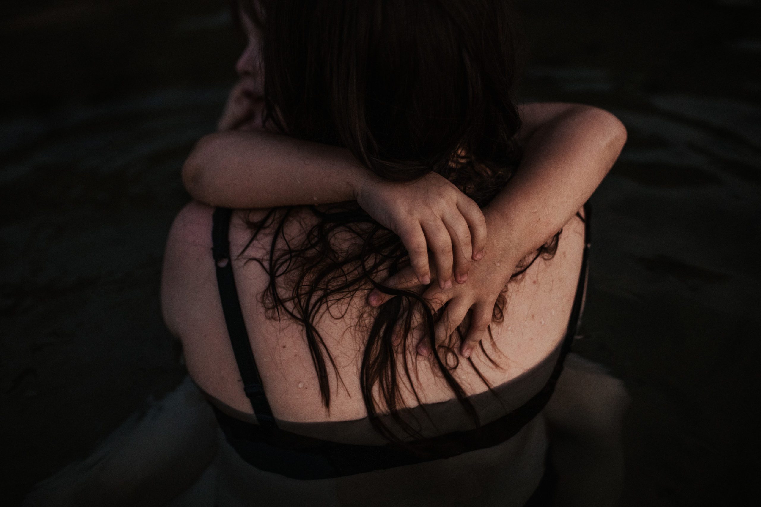 Close up of a young girls hands grasp around her mothers neck showing natural family photography and real interactions