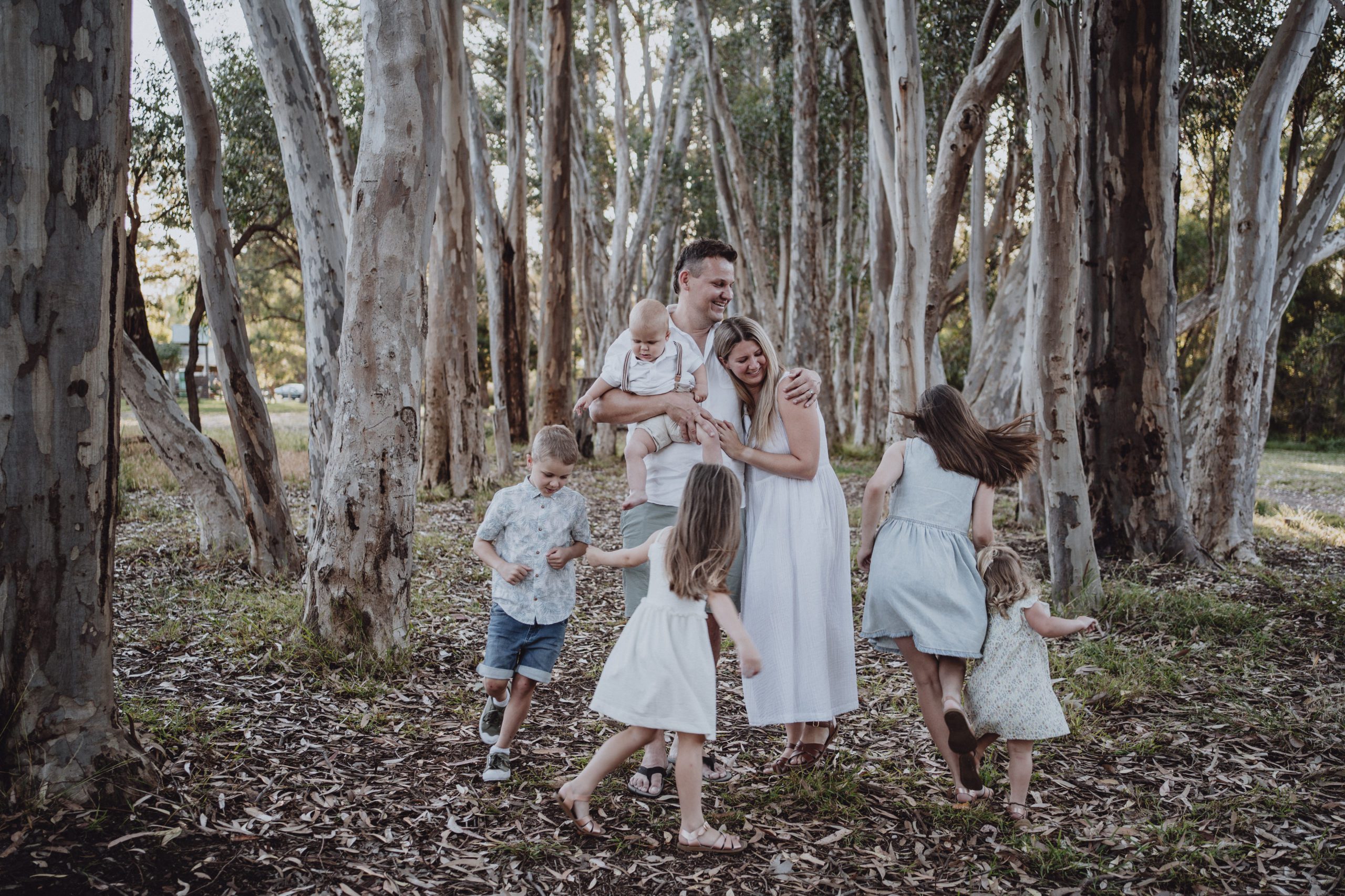 Claire and her family of five kids running around in amongst tall gum trees at a Christmas Mini Session in Melbourne