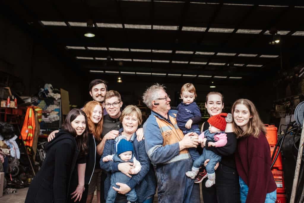A group family photo of a family standing in a mechanic shop
