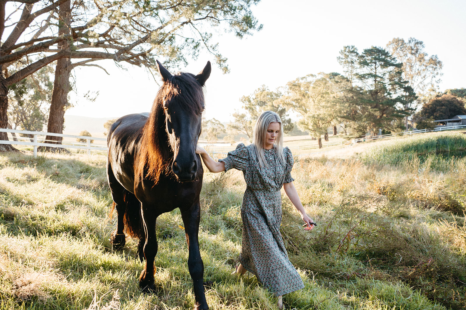 a woman leads her horse through a paddock in Healesville