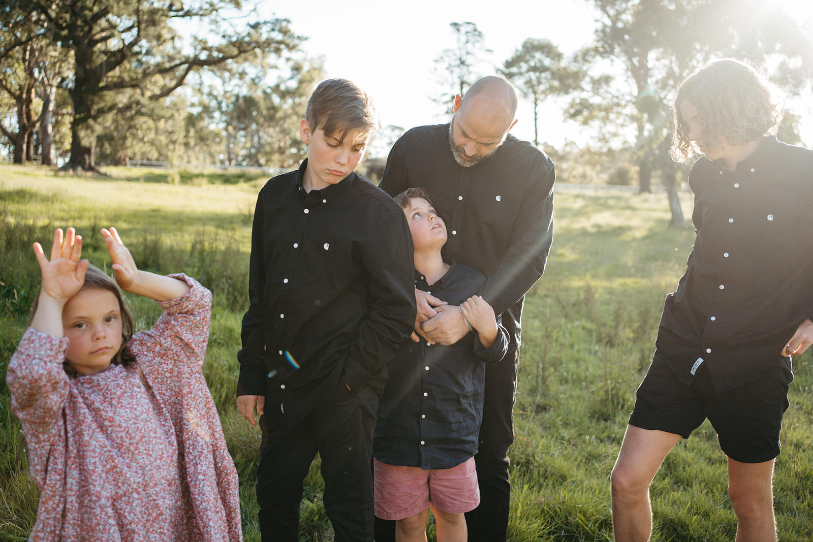 informal documentary image of a dad and his children outdoors in a paddock