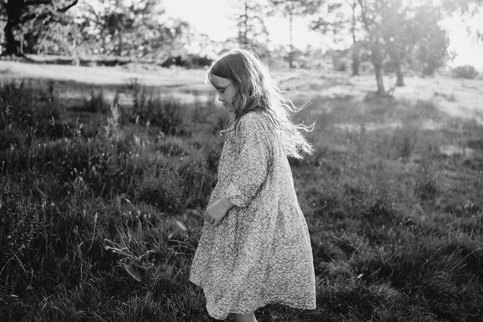 black and white of a young girl in a long sleeve pale dress she is looking to the left