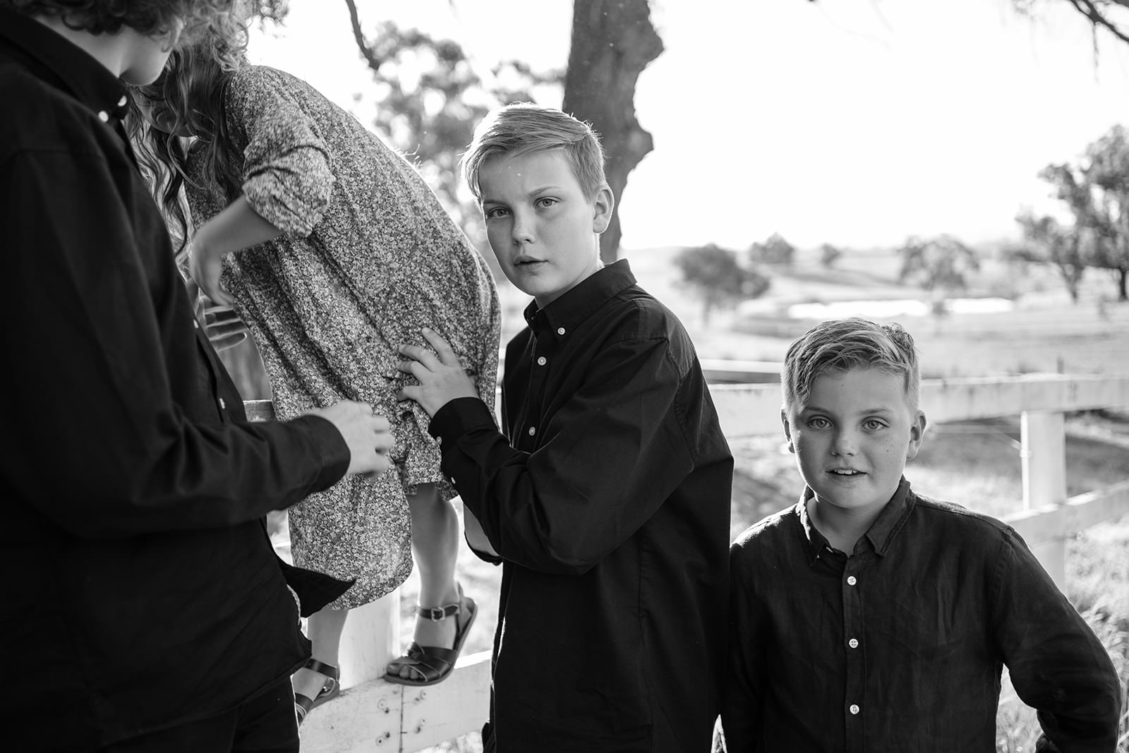 a black and white image of two boys and their sister who is being held just outside of the frame