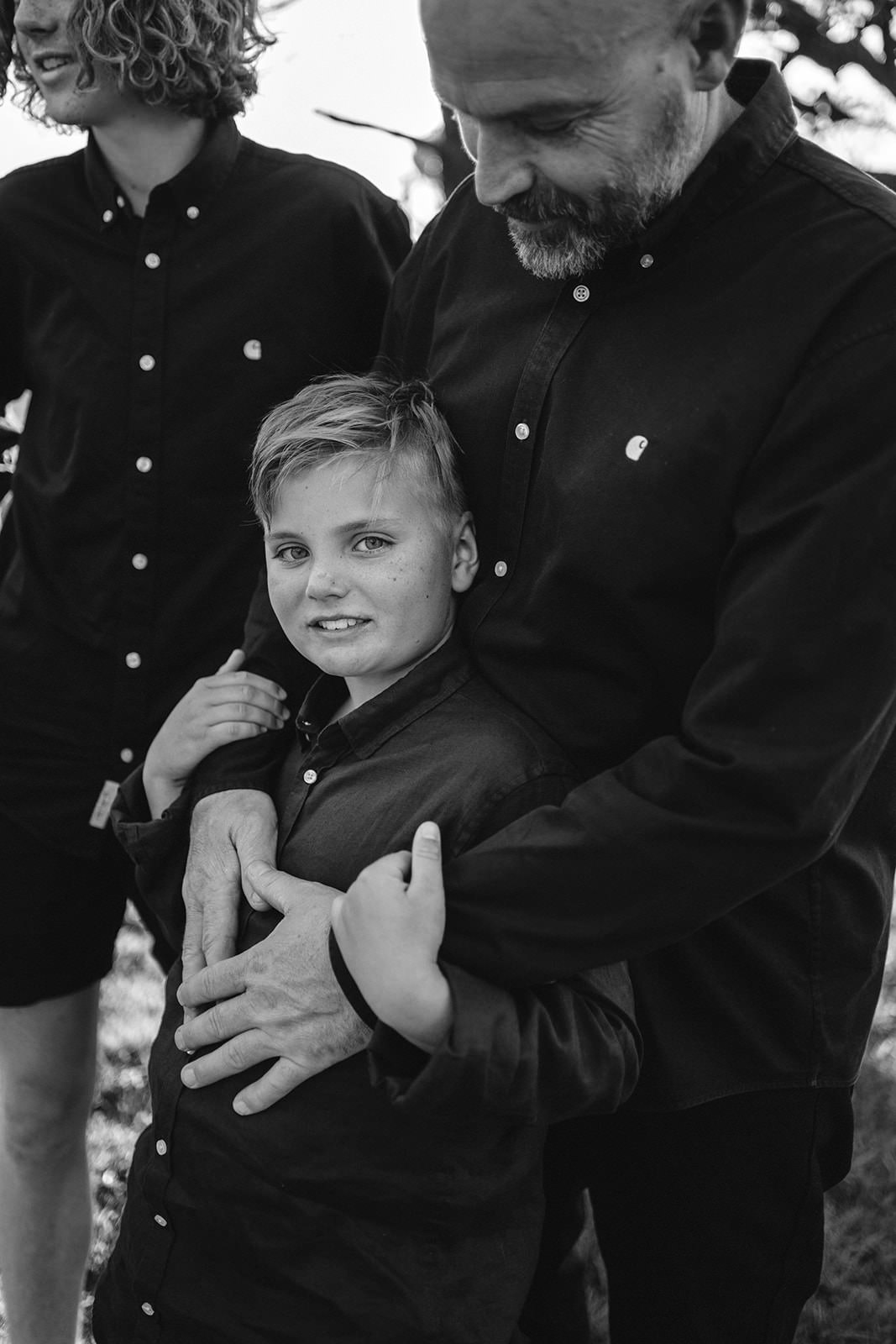 a young boy with his fathers arms around him