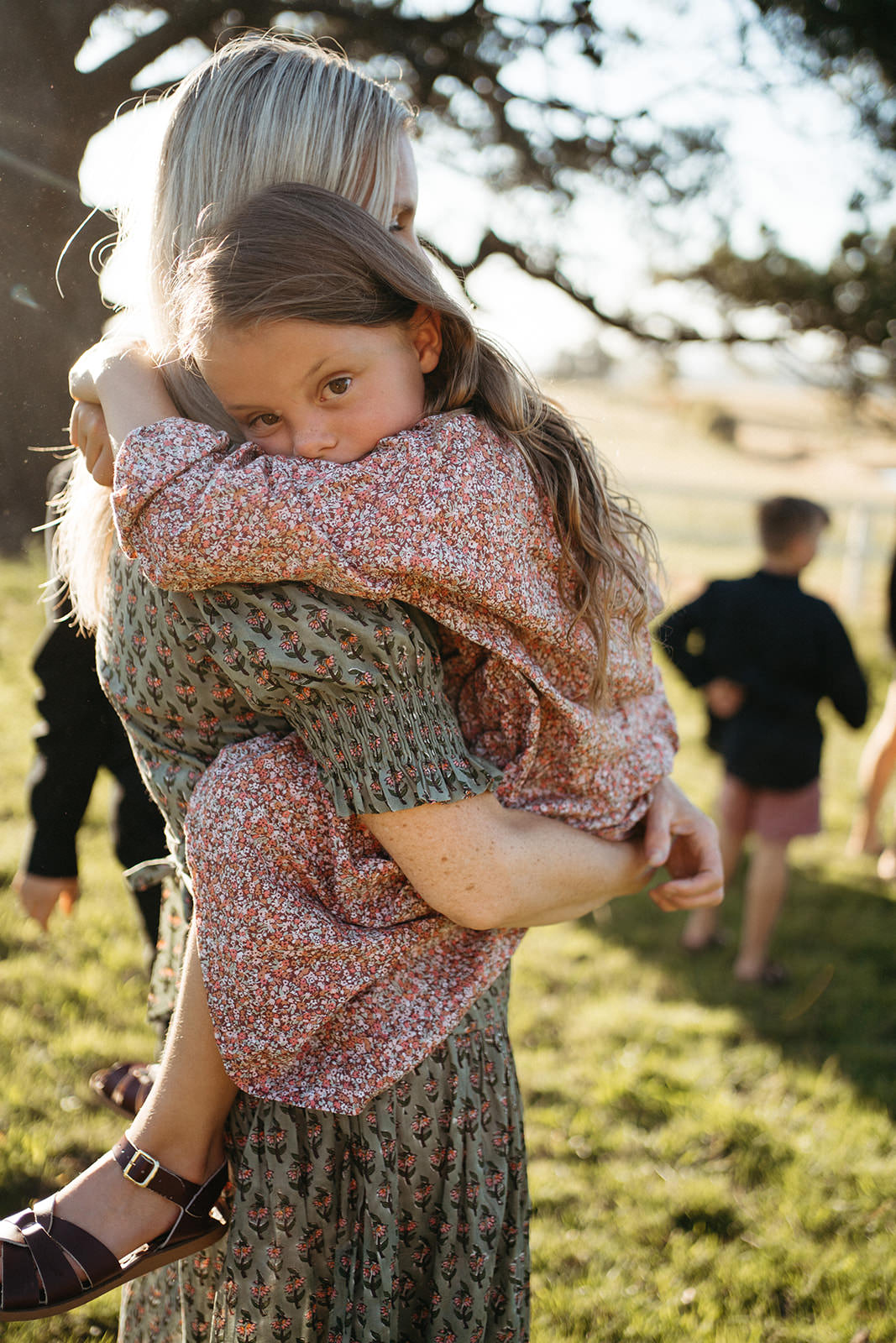 a young girl clings to her mother