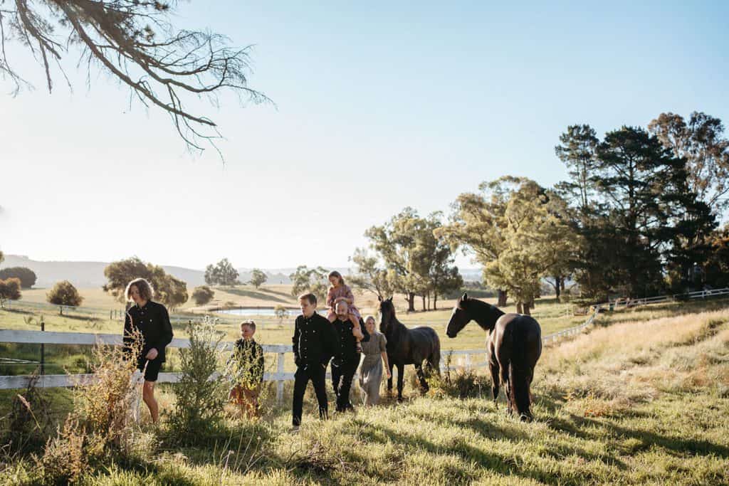 a family walks in a paddock with horses