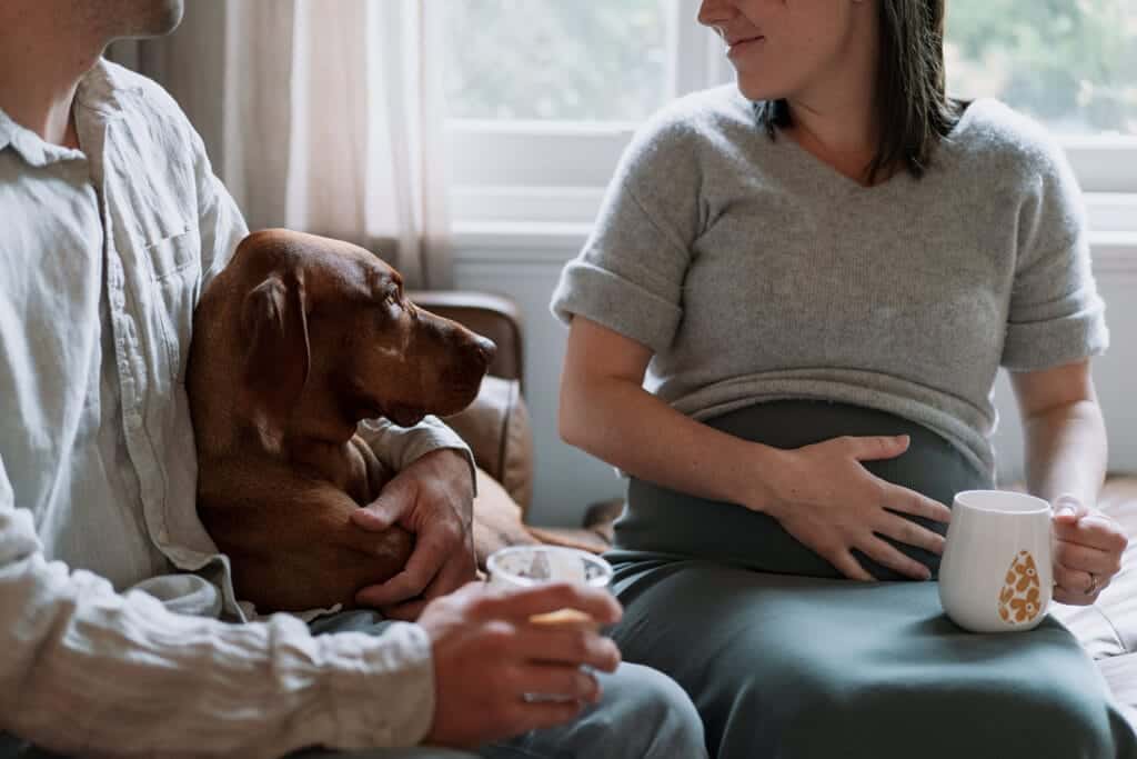 faceless image of a pregnant couple with a dog