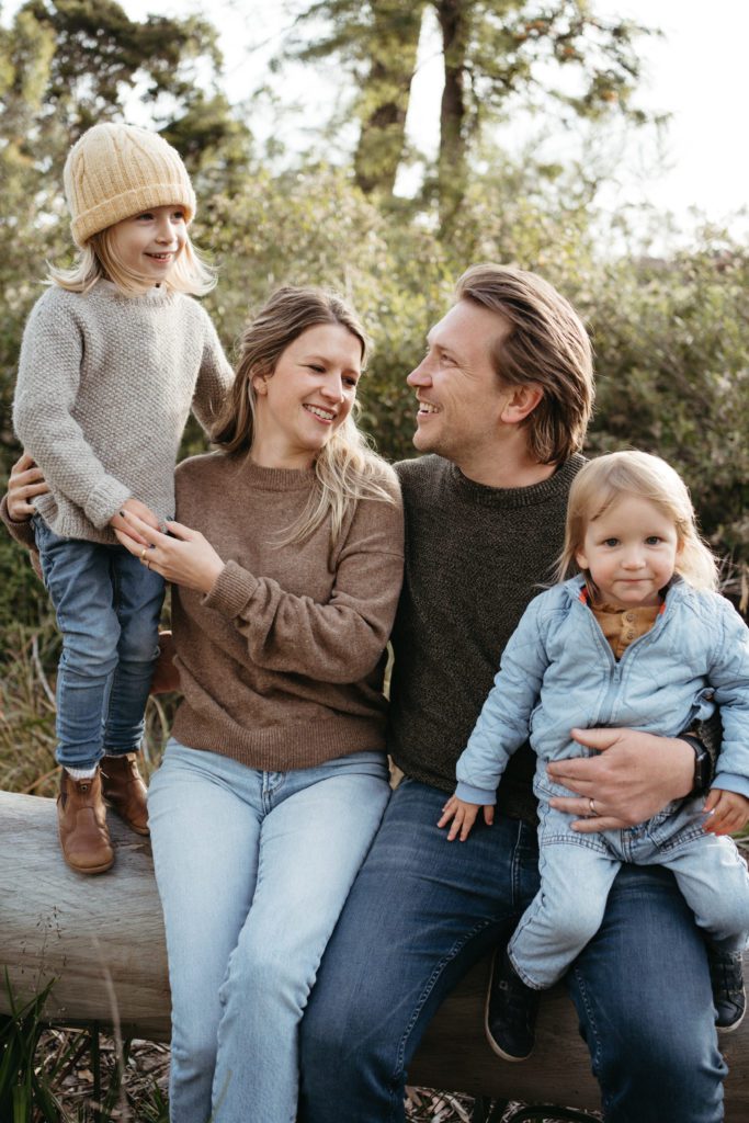 winter family photoshoot with a family of four a mother and father and two sons wearing warm clothes