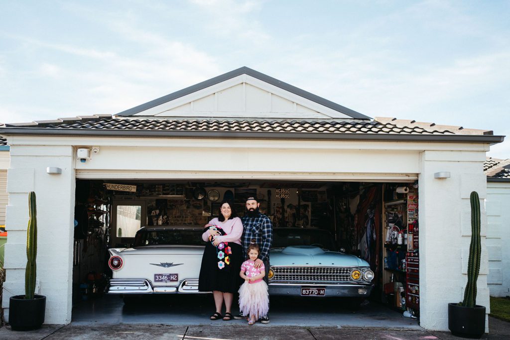 a family of four stands in-front of a garage wearing pink and black and blue