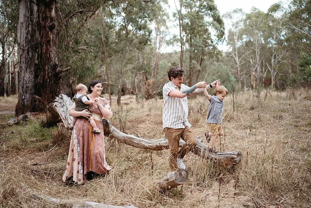 a family of four climb a log in australian bushland