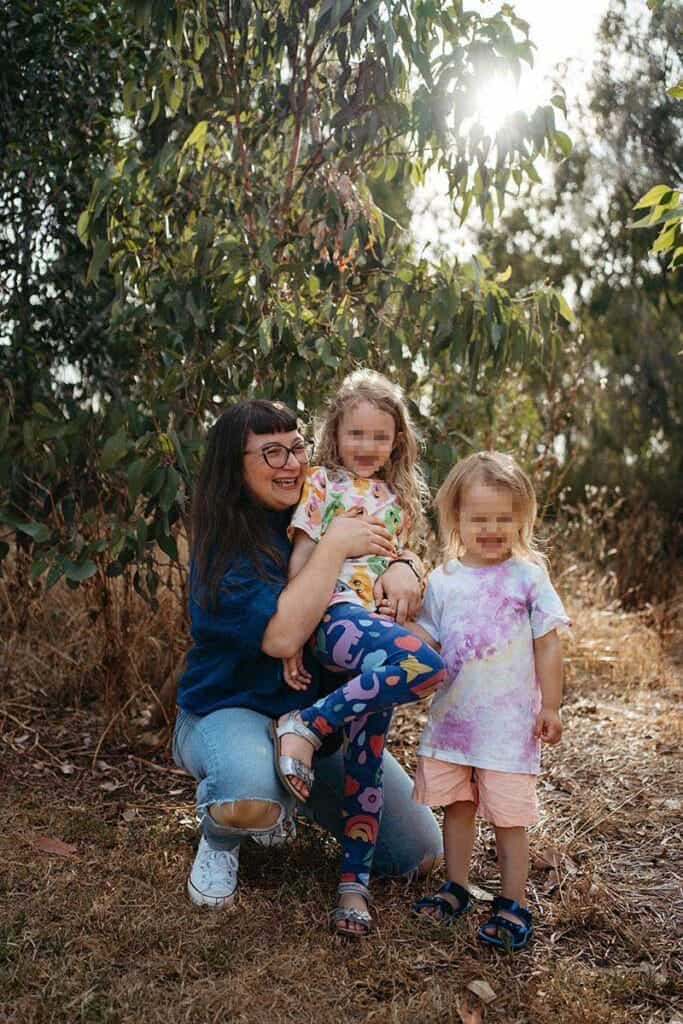 mother smiles with her two children with bright clothing