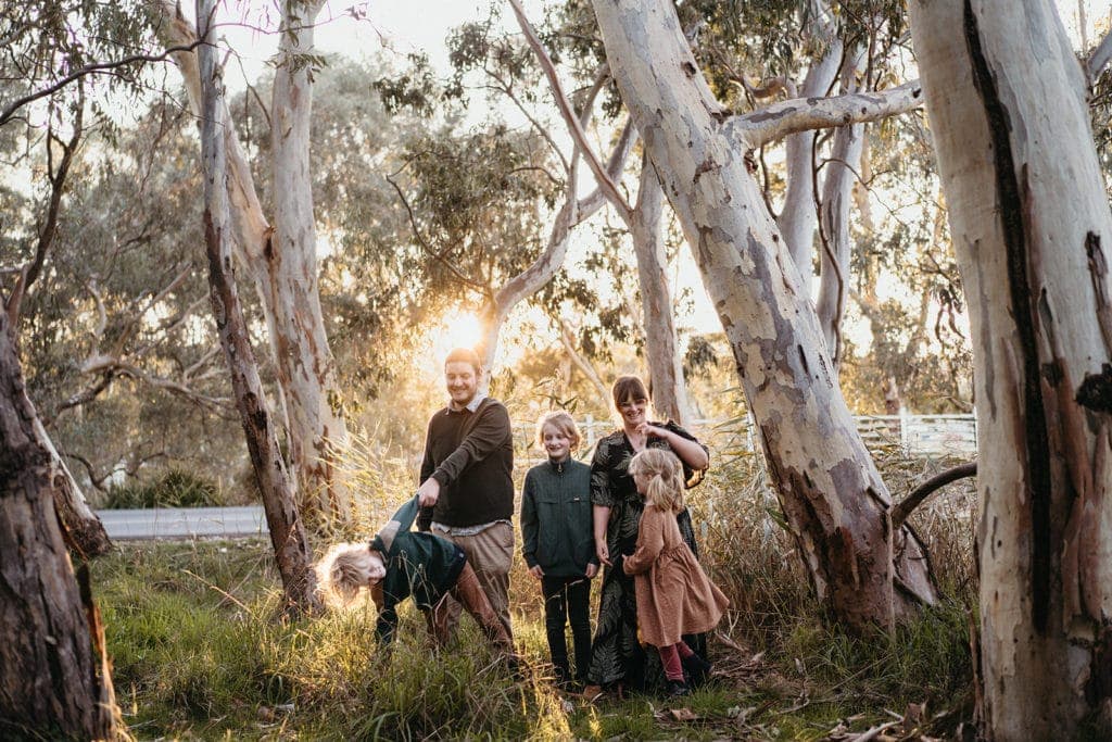 Melbourne family playing in bushland with golden light behind them