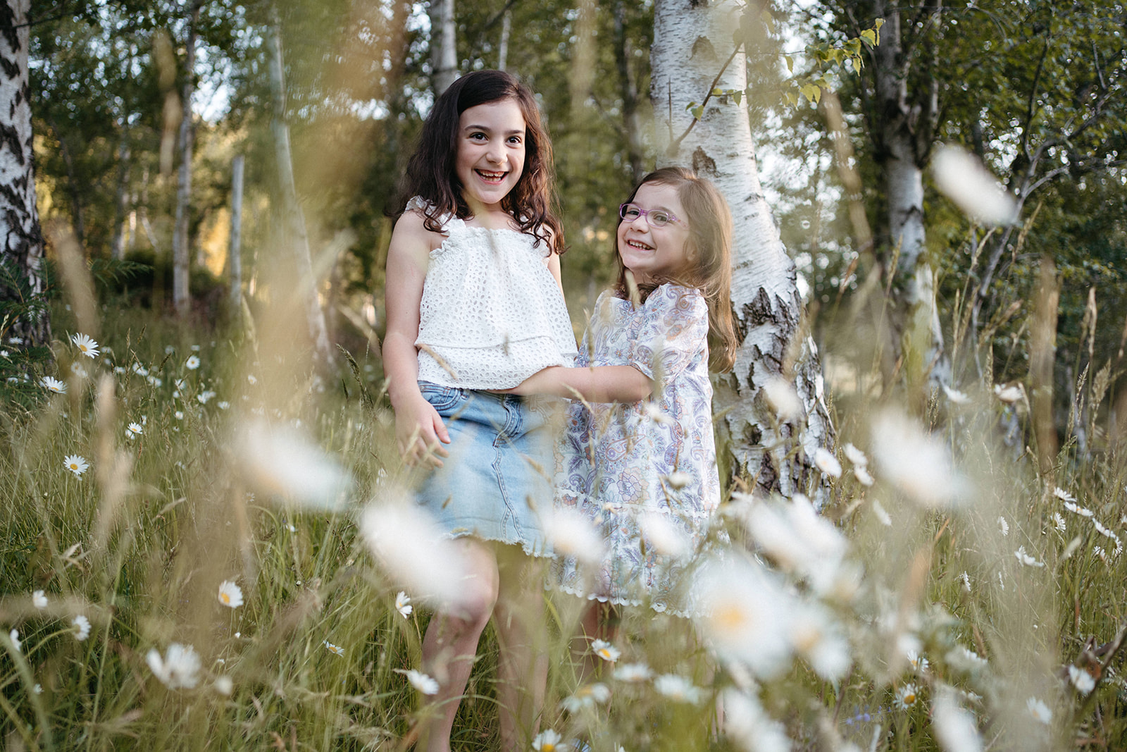 two girls play in a field of daisies