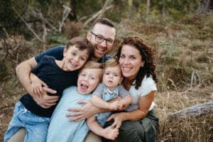 a Melbourne family look at the camera they are cuddling closely