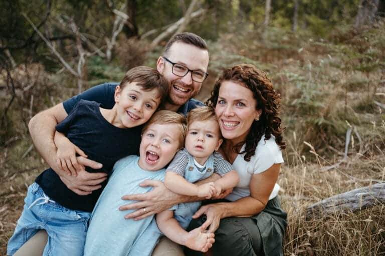 a Melbourne family look at the camera they are cuddling closely