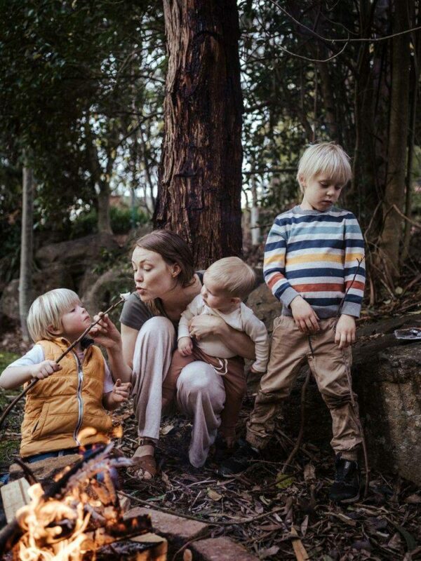 Melbourne family photography can look like a mother eating a marshmallow with her sons in front of a campfire