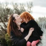 mother kisses her daughters head