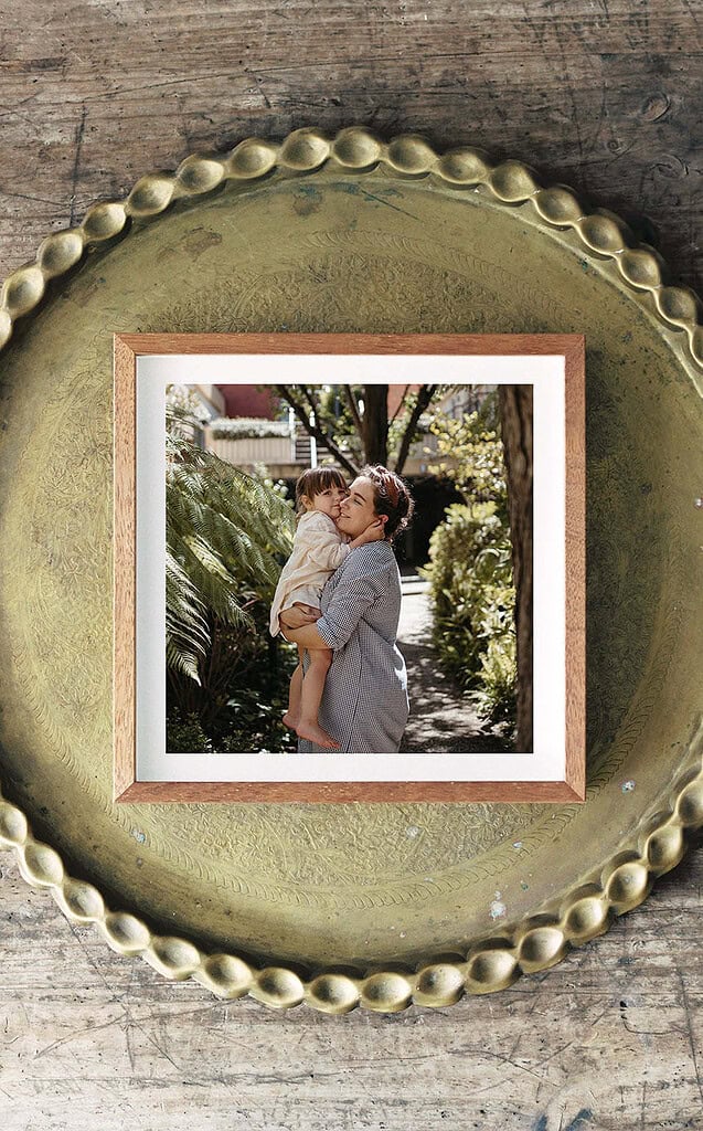 framed image of a mother holding her young daughter the wooden frame is sitting on a green plate