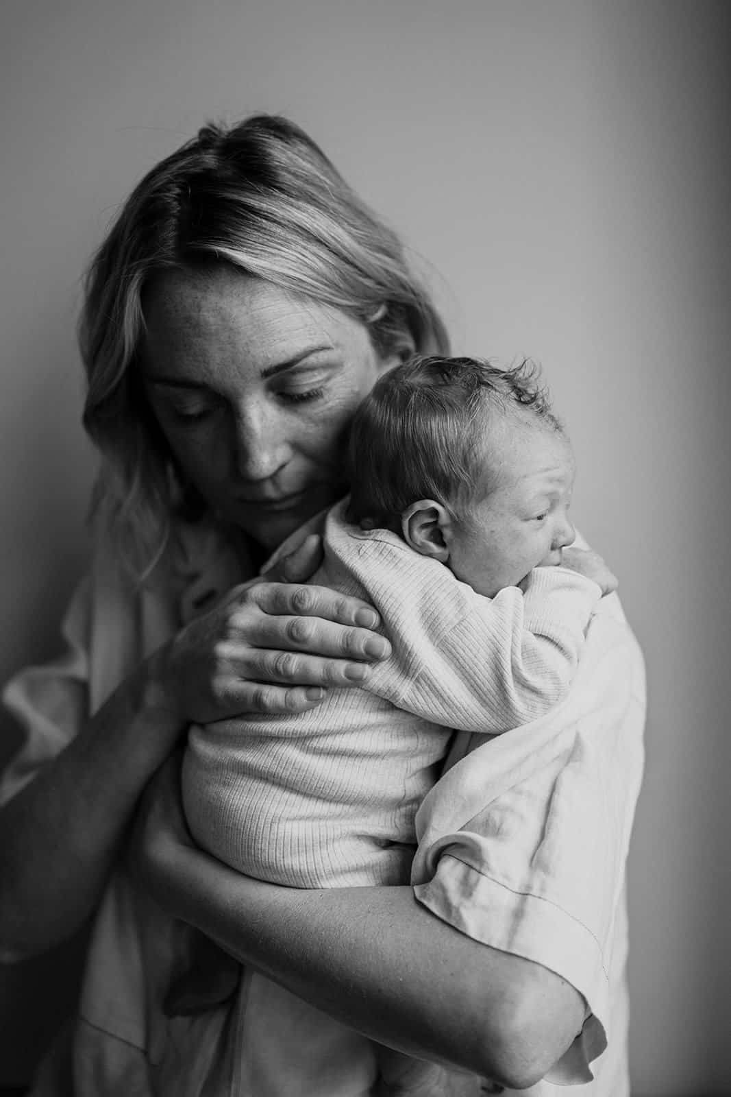 newborn photographer melbourne a mother holds her young baby on her chest