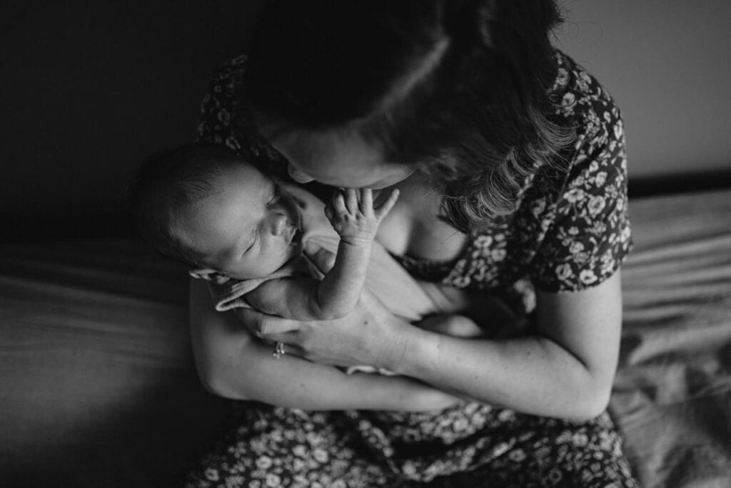 a newborn baby reaches up to touch his mothers face