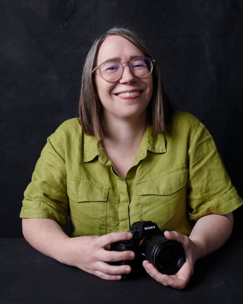 portrait of Bec Matheson Melbourne family photographer she is wearing a green shirt and smiling and holding a camera