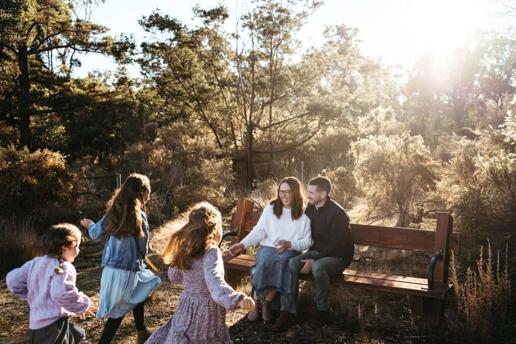 three girls run towards their parents in the afternoon sunshine