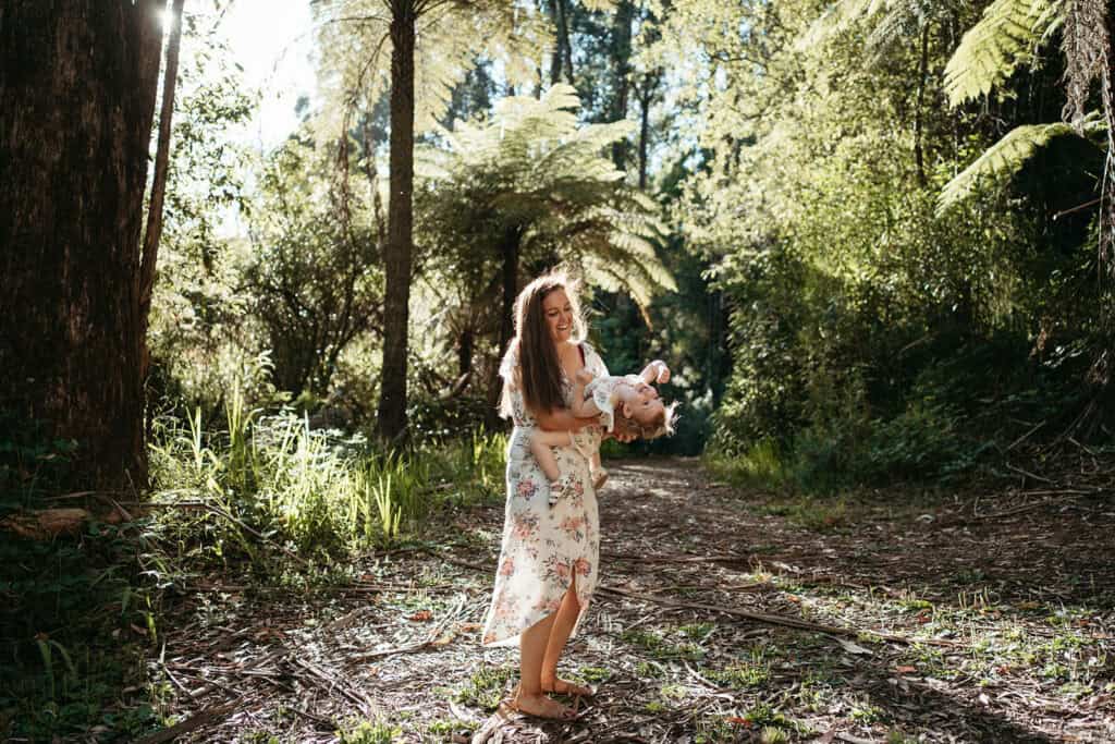 Mother holds her sun in dappled light in Australian bushland