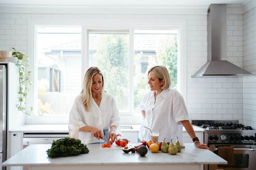 Two women chop vegetables in a Melbourne kitchen