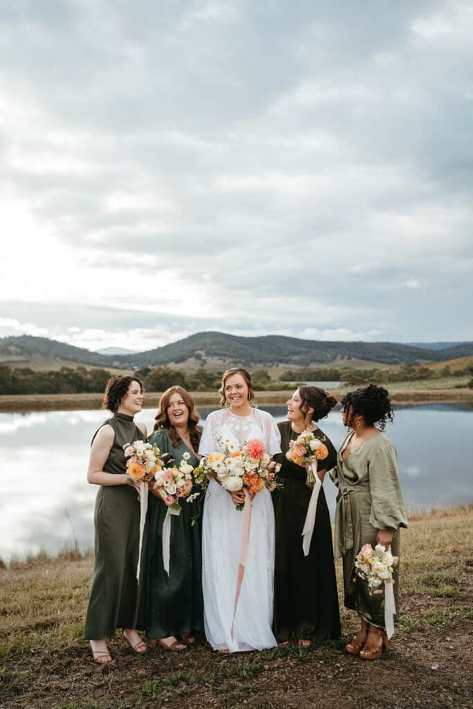 bridesmaids and bride infront of a lake