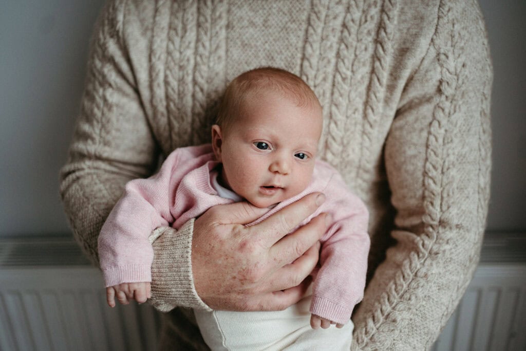 newborn girl held in her fathers arms