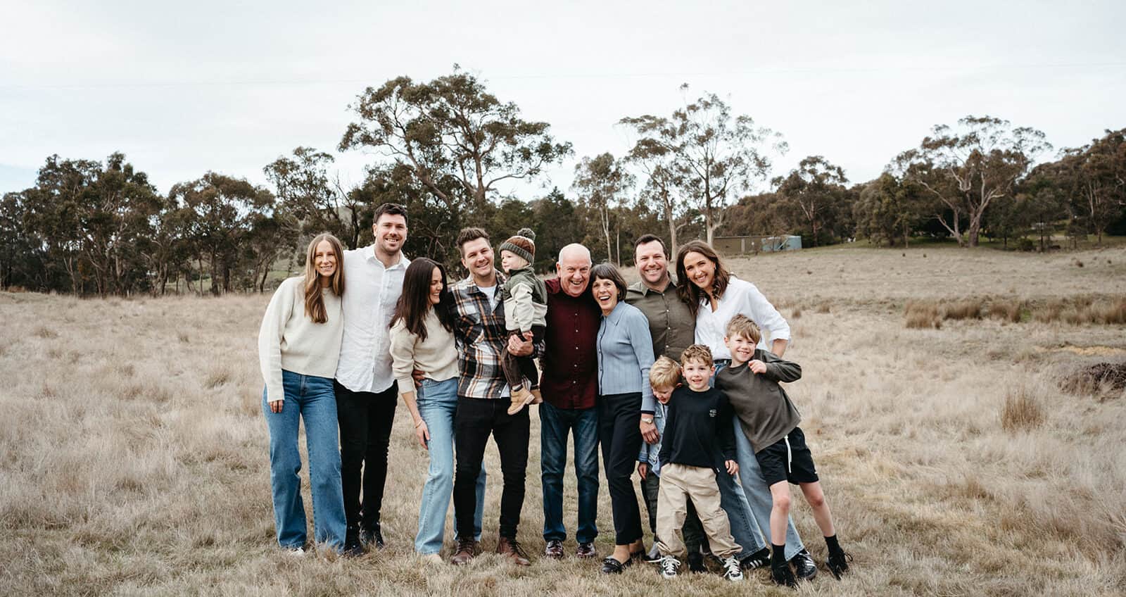 a large family photo of a group wearing coordinated clothing on a farm standing together smiling