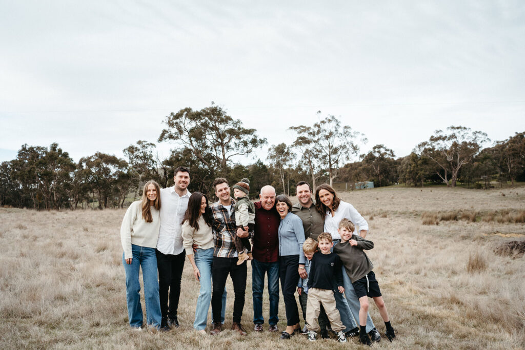 a large family photo of a group wearing coordinated clothing on a farm standing together smiling