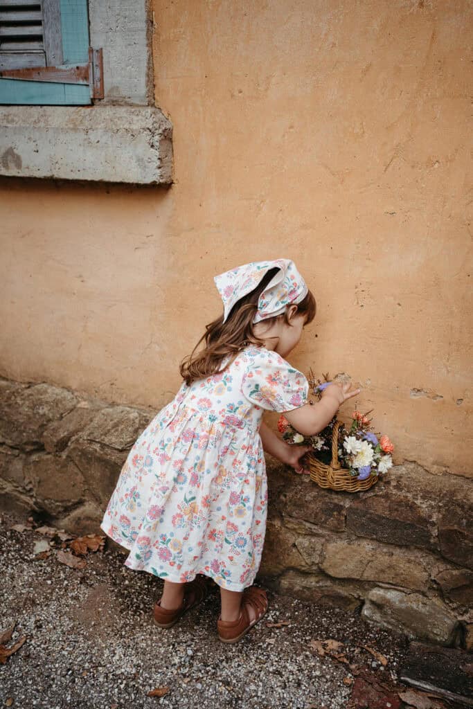 a girl in a floral dress picks flowers kids clothing brand