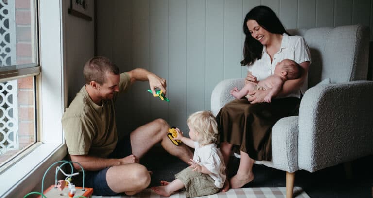 Playful in-home newborn session in Melbourne with dad flying toy airplane for toddler during natural family photography
