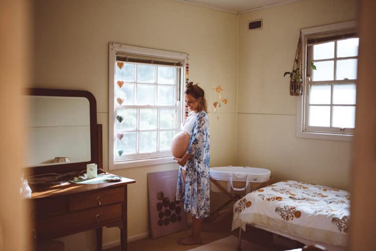 maternity photo of a mother in a nursery when to book newborn photographer Melbourne pregnant woman at home