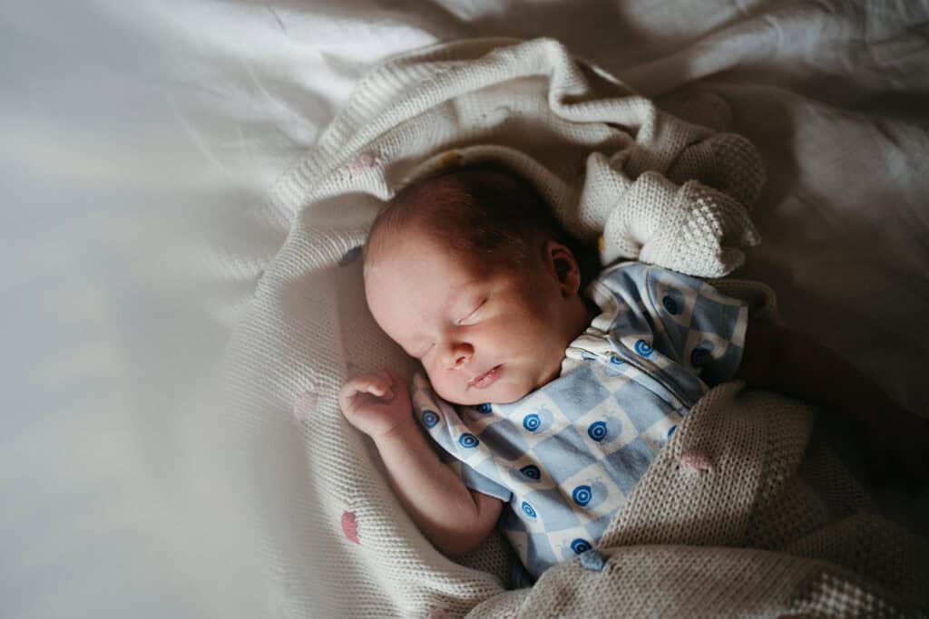 a newborn baby sleeps on a bed looking peaceful