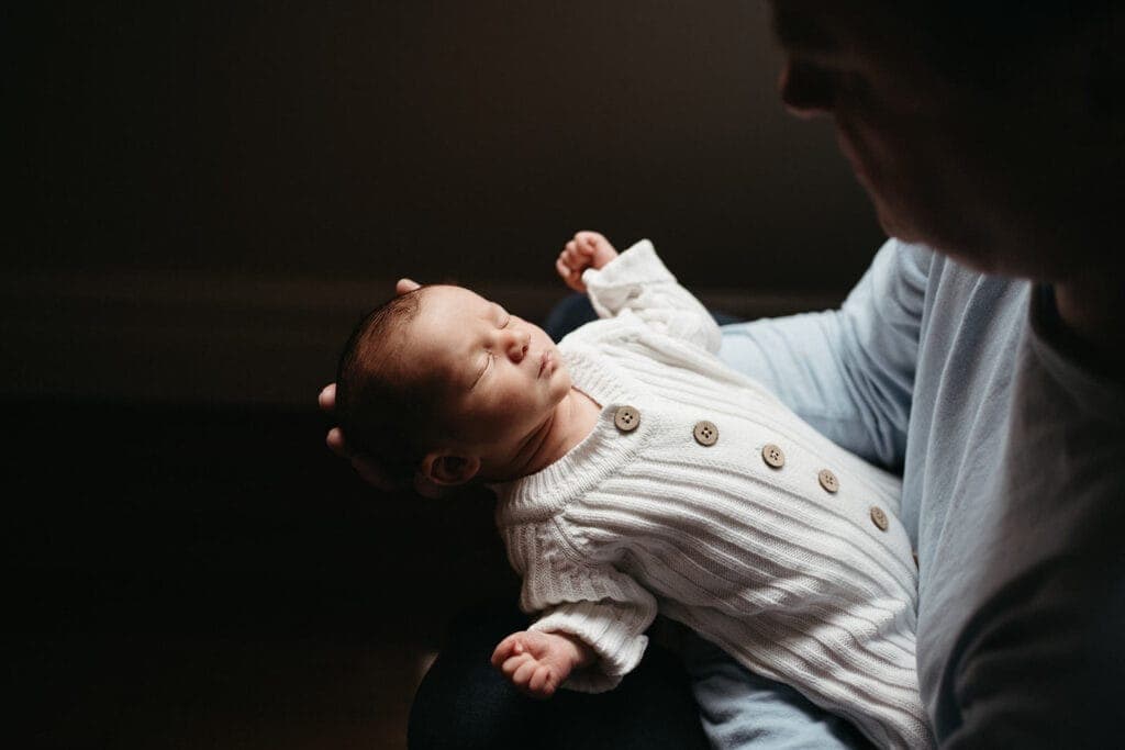 Newborn in neutral knit onesie during cosy in-home photo session