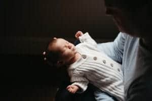 Newborn in neutral knit onesie during cosy in-home photo session