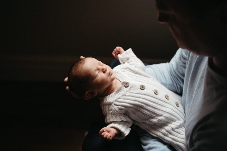 Newborn in neutral knit onesie during cosy in-home photo session