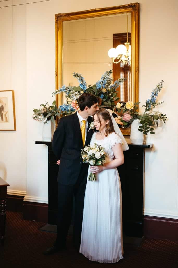a young couple getting married at the registry office in melbourne the groom is kissing the brides head