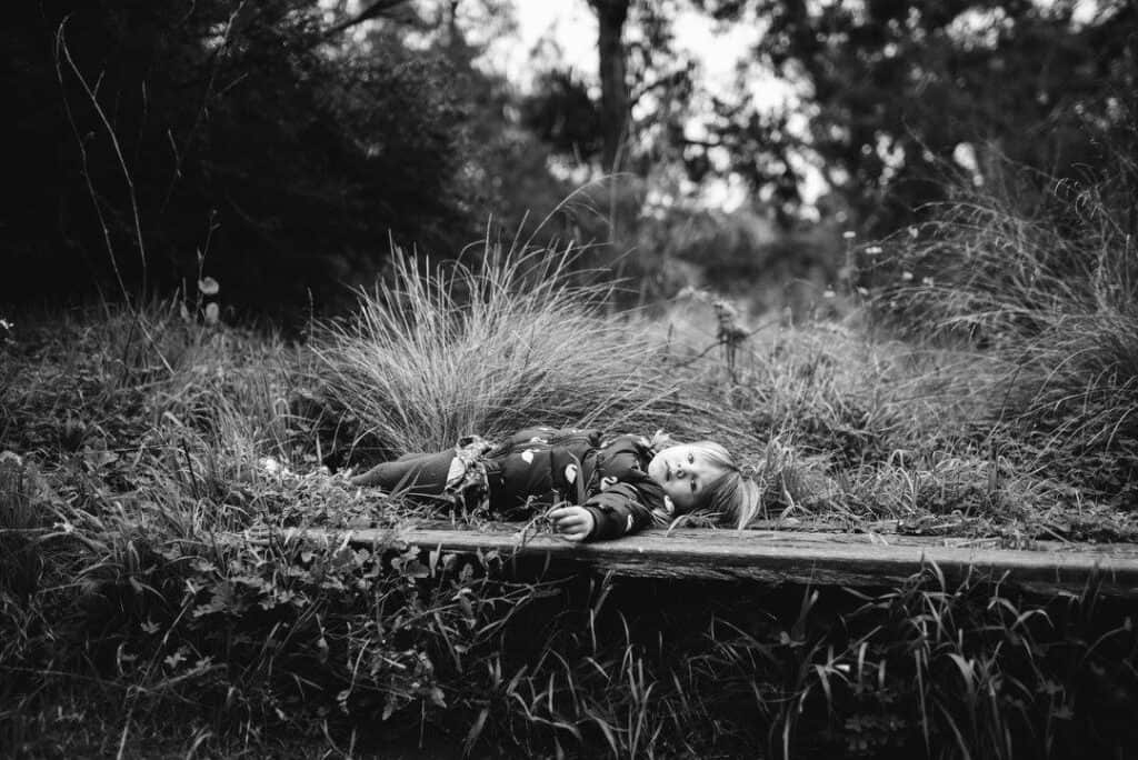 a four year old lies on a bench in amongst grasses in melbourne bushland