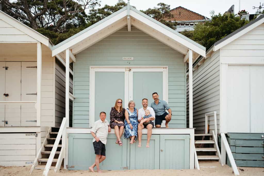 a family sit on a light blue melbourne beach box