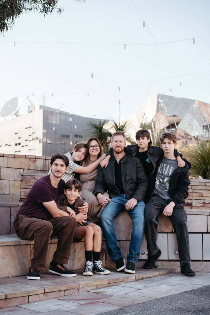 a family with six teenage boys sits at federation square melbourne at a family photoshoot