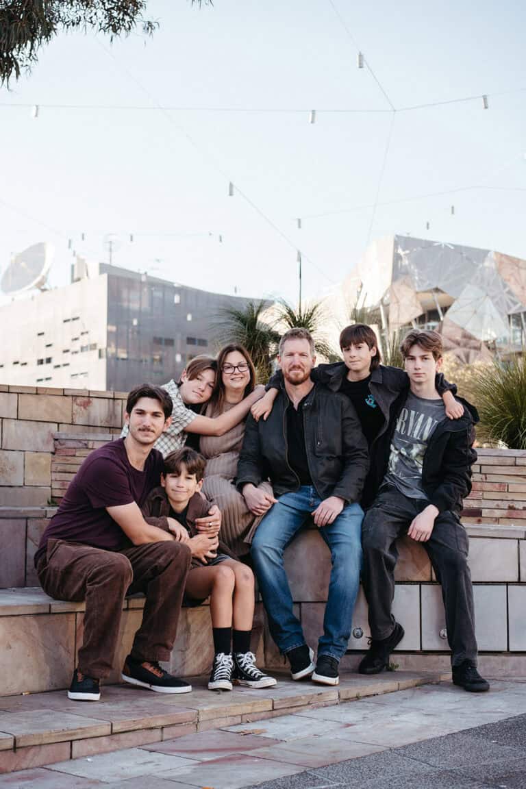 a family with six teenage boys sits at federation square melbourne at a family photoshoot