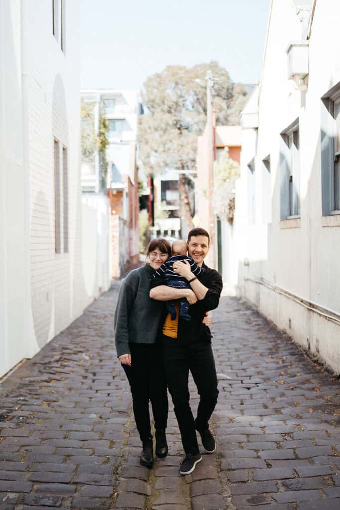 a couple with a baby walk in a melbourne laneway they are laughin