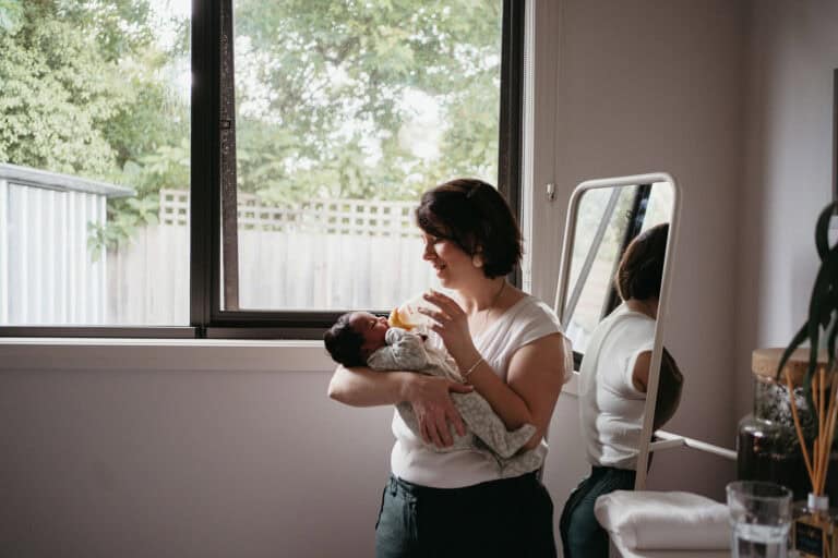 a melbourne postpartum doula holds a newborn baby and feeds the baby a bottle