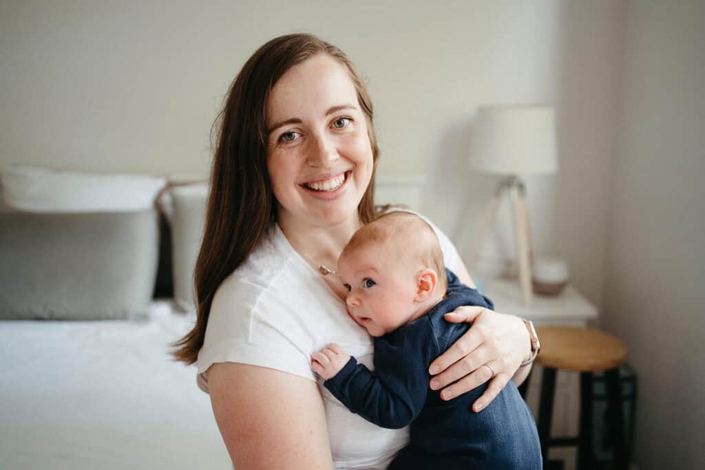 a mother holding her new baby smiles at the camera