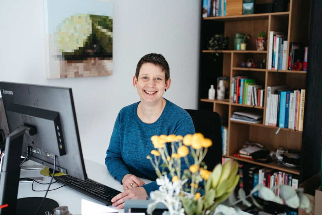 portrait of a melbourne business woman at her computer she is smiling and there are flowers in the foreground