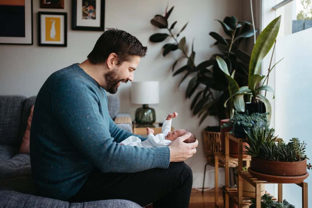 a dad holding a newborn baby who is stretching